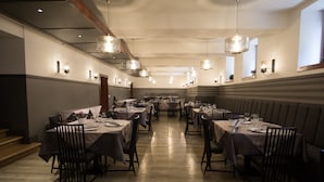 A spacious dining area with multiple tables and chairs, overhead lighting, and a polished wooden floor. - Hotel Savoy (Timisoara)