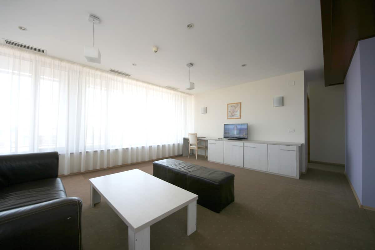 Un salon avec un canapé, une table basse, un téléviseur et un meuble.