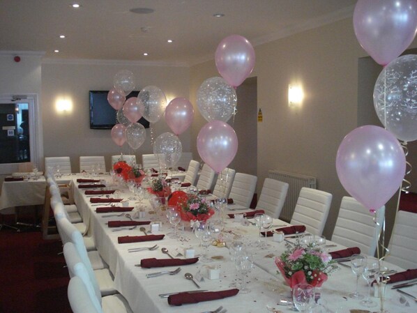 A banquet hall with tables set for a formal event, featuring white tablecloths, red napkins, and floral centerpieces. - Eastbourne Riviera Hotel (Eastbourne)