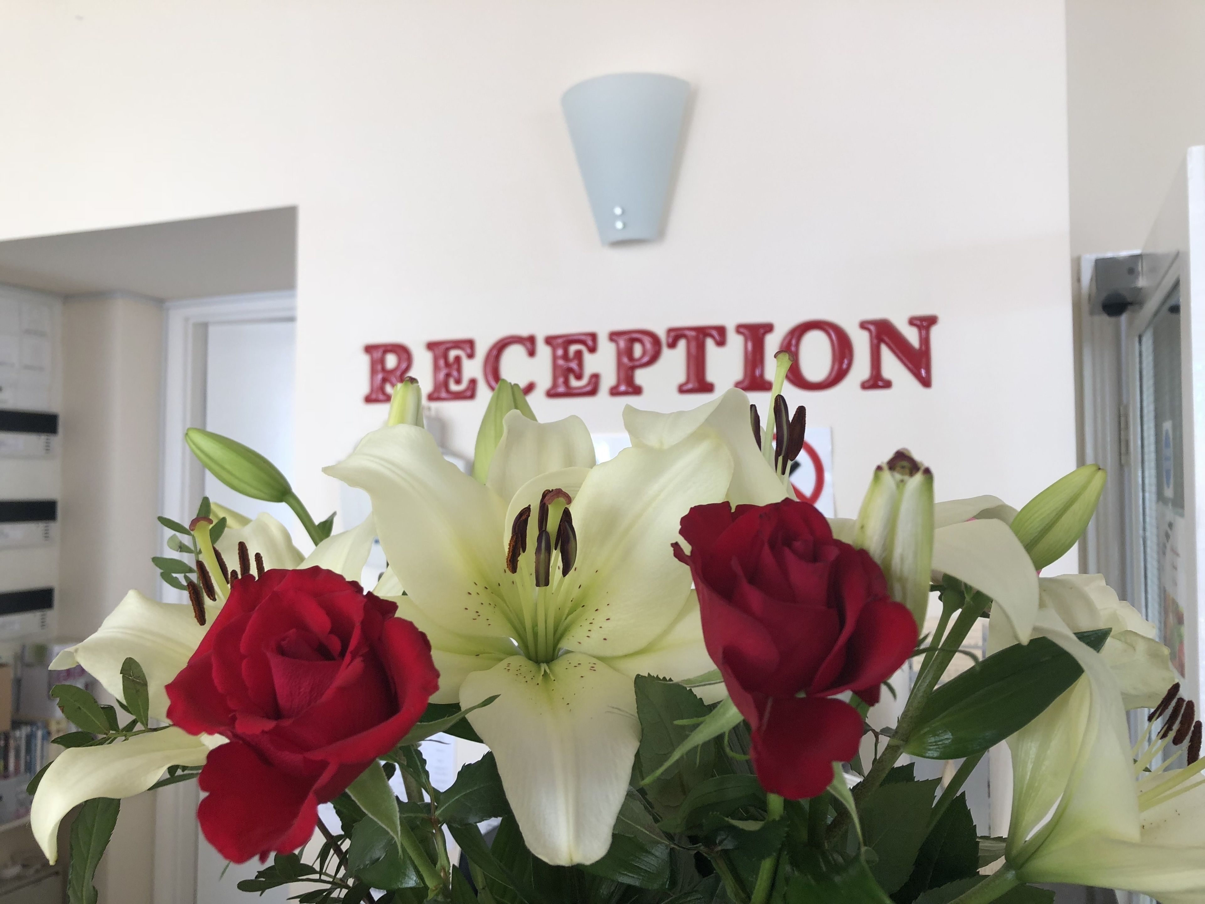 A reception area with a sign that reads "RECEPTION" and a bouquet of flowers in the foreground.