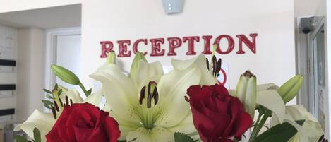 A reception area with a sign that reads "RECEPTION" and a bouquet of flowers in the foreground.