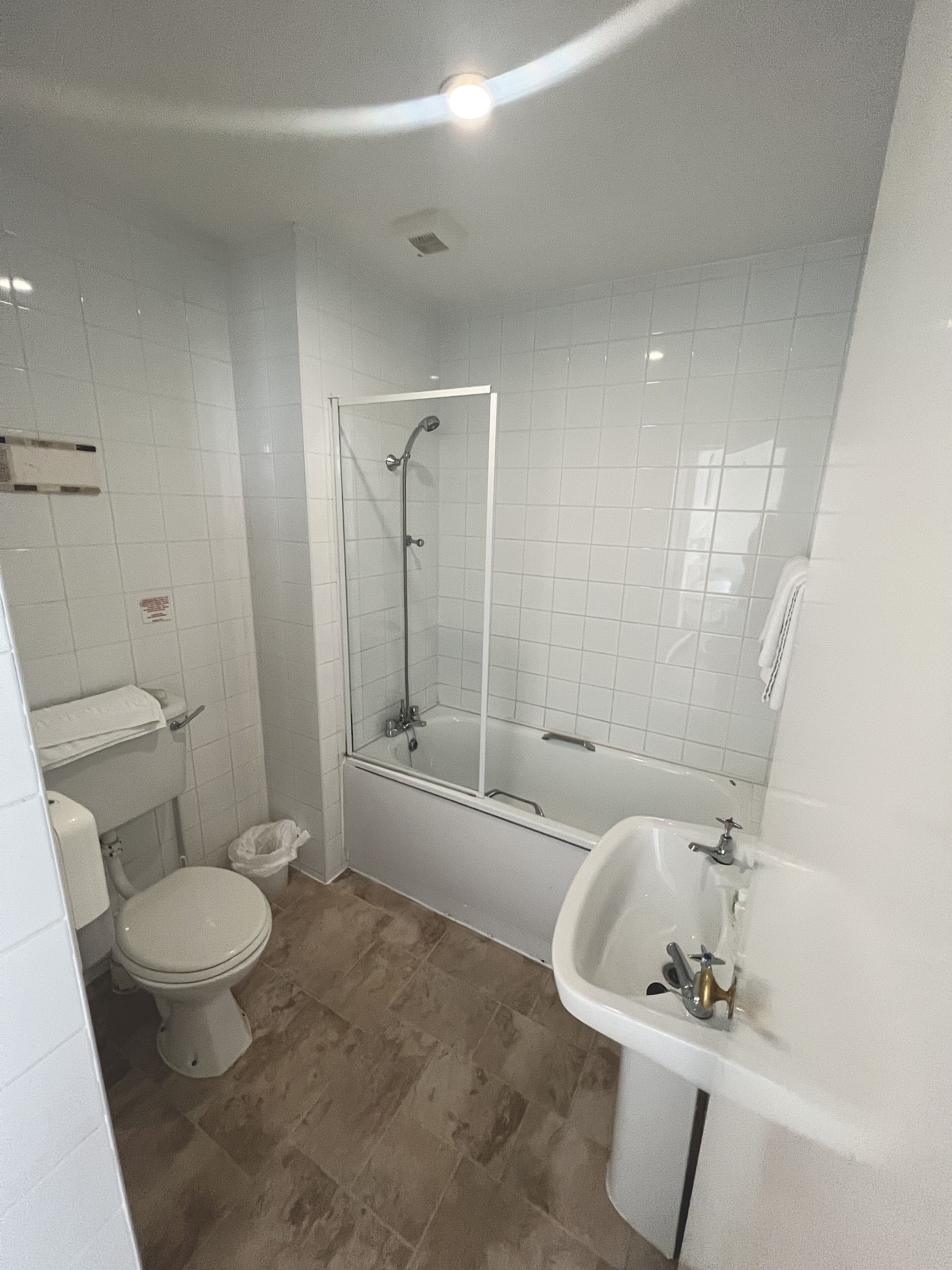 A bathroom with a toilet, a shower enclosure, and a sink.