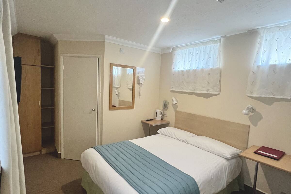 Une chambre d’hôtel avec un lit, une table de chevet, une lampe et un miroir.