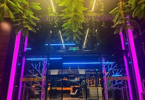 A hotel entrance with a glass door, neon lights, and indoor plants. - Best Hotel (Ploiesti)