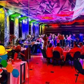 A restaurant with tables and chairs, a stage for performances, and a colorful ceiling. - Best Hotel (Ploiesti)