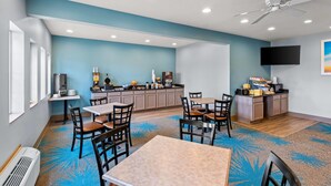 Habitación de hotel con comedor, kitchenette y ventilador de techo.