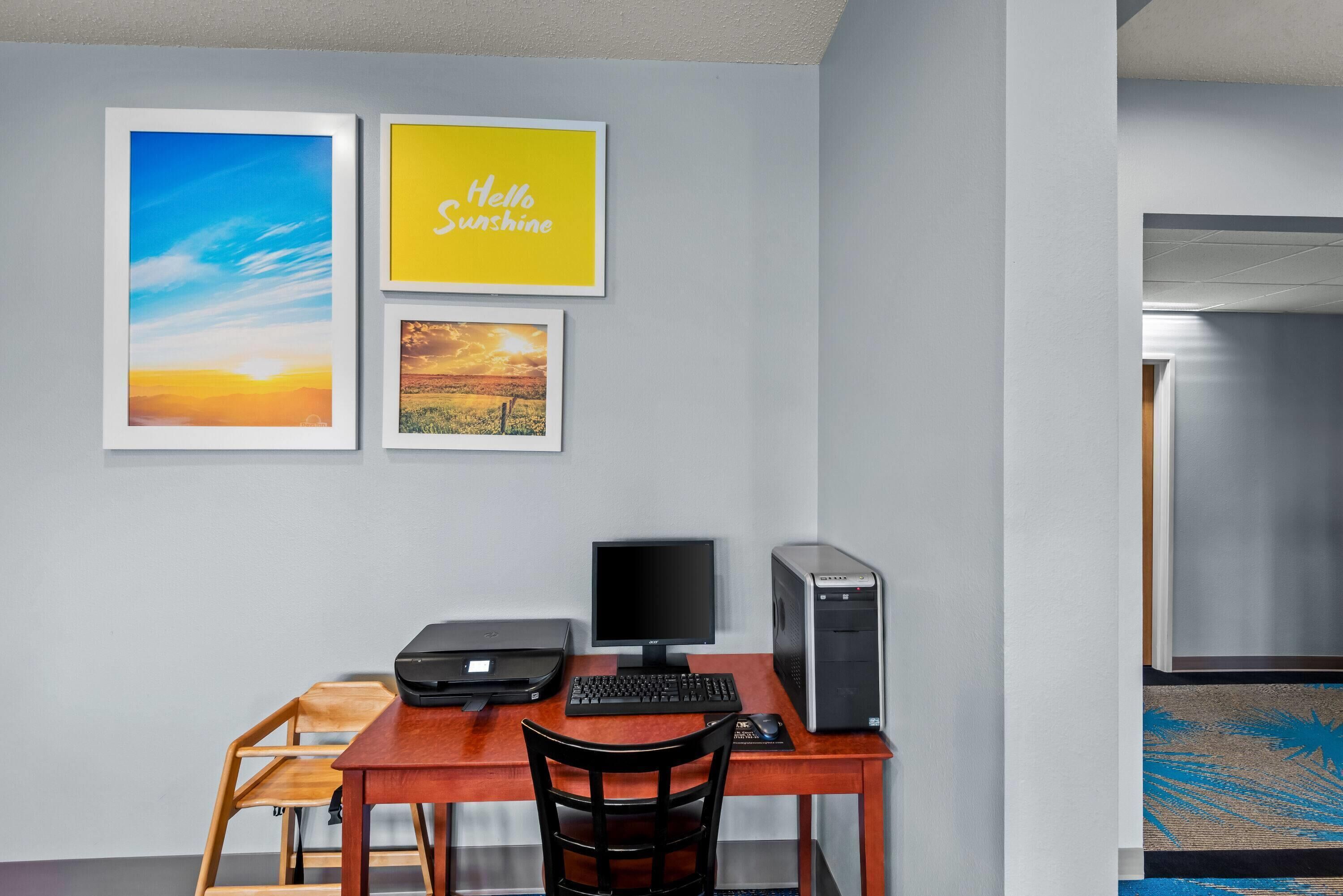 A workspace with a desk, computer, and chair, and three framed pictures on the wall.