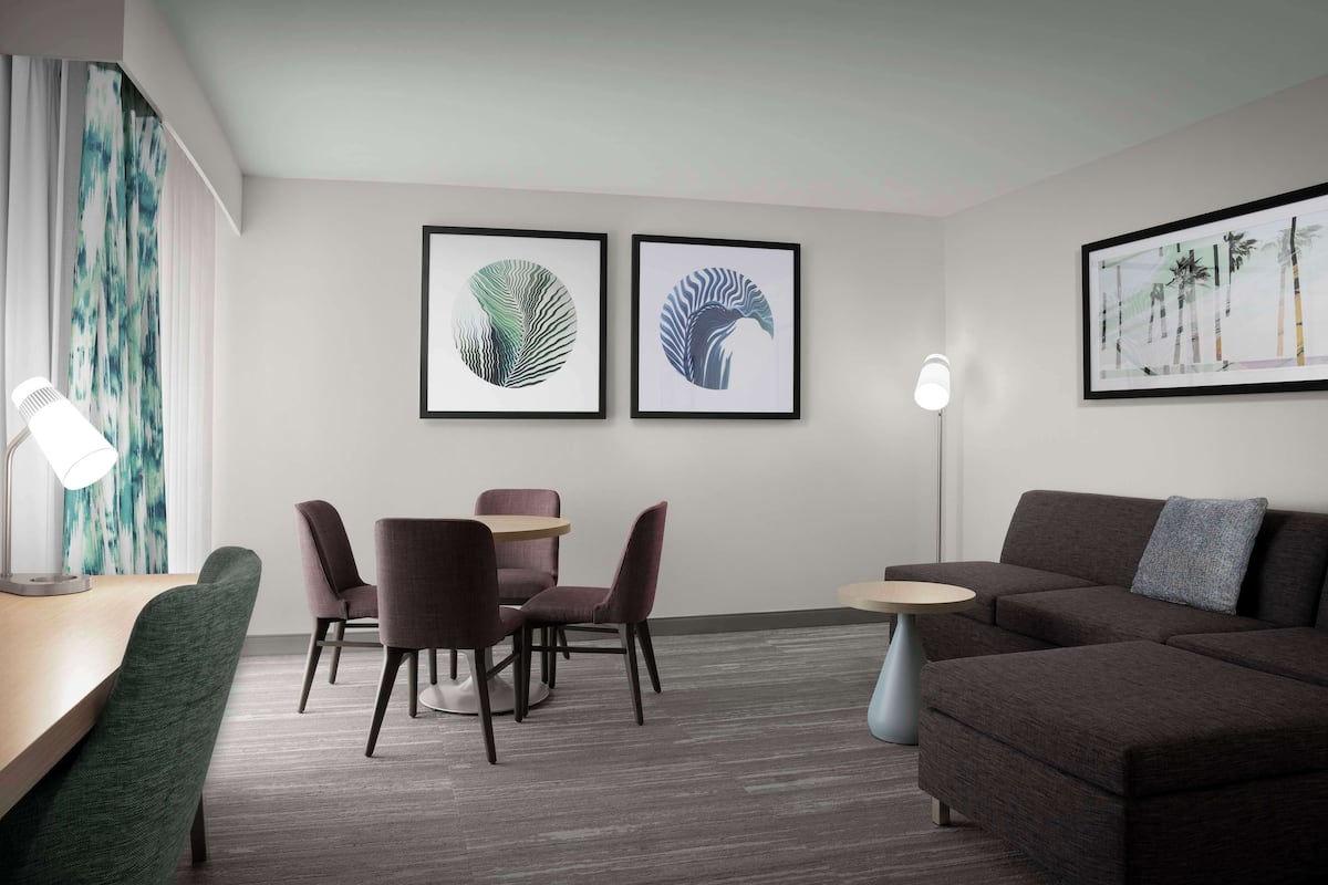 A modern room with a dining area, a sofa, and two framed artworks on the wall.
