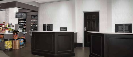 A hotel lobby with a reception desk, a minibar, and a bar area.
