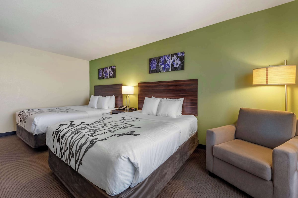 A hotel room with two beds, a sofa, and artwork on the walls.