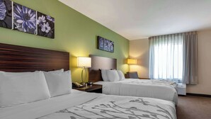 Habitació d'hotel amb dos llits, un panell de capçalera de fusta, una tauleta de nit amb un telèfon, dues làmpades penjades a la paret i una finestra amb cortines.