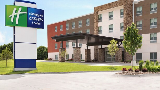 A Holiday Inn Express & Suites hotel with a modern building facade, a covered entrance, and a well-maintained lawn.