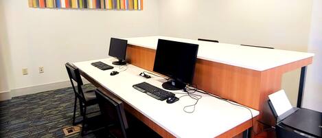 A conference room with a long table, two computer monitors, a keyboard, and a mouse.