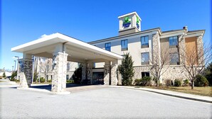 A modern hotel with a covered entrance, stone facade, and a sign indicating it is part of the Hampton Inn Express.