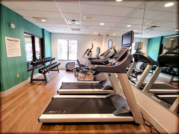 A fitness center with treadmills, dumbbells, and exercise equipment.