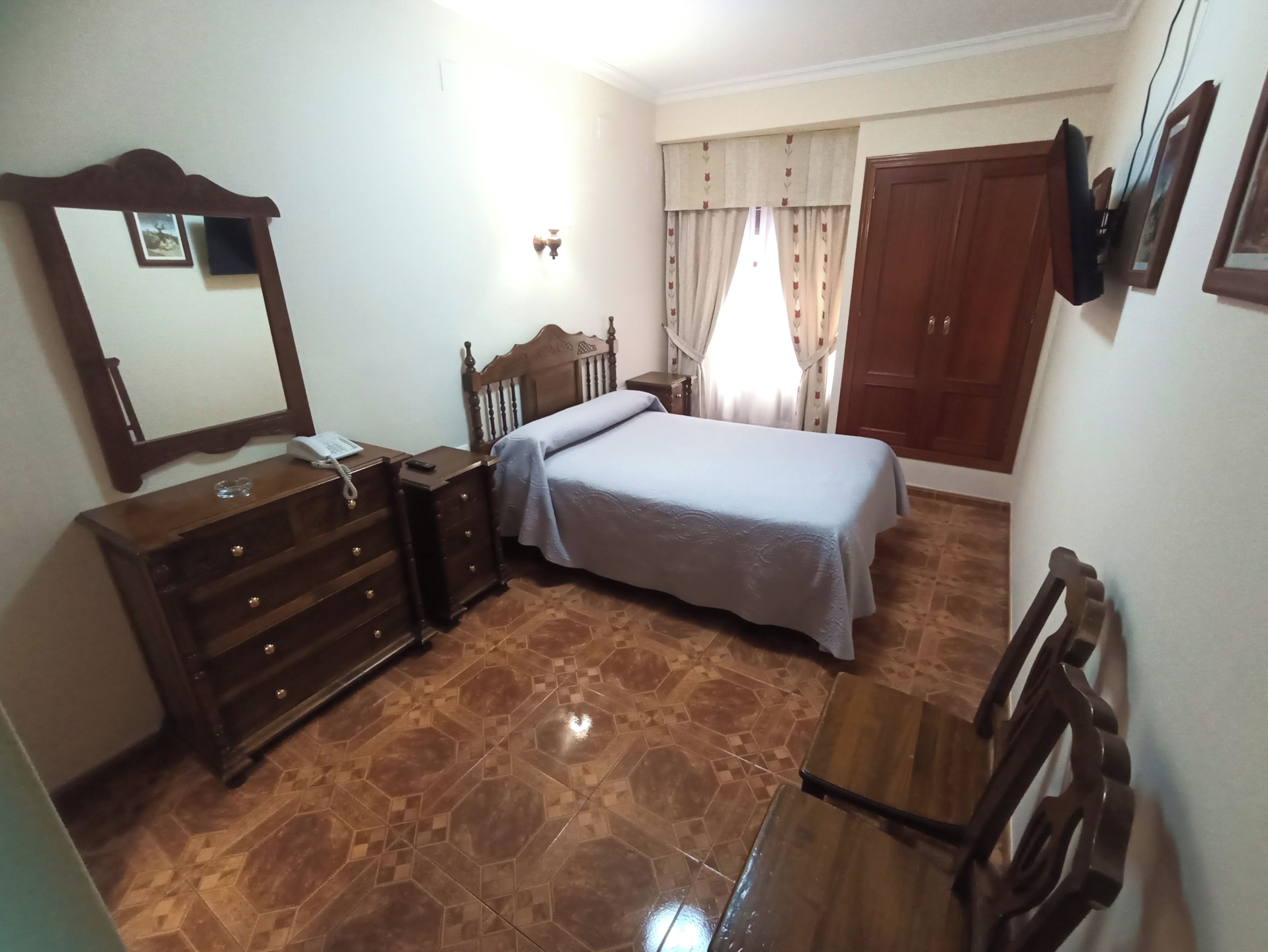 Quarto com cama, penteadeira, espelho e guarda-roupa de madeira.