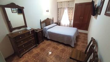 Quarto com cama, penteadeira, espelho e guarda-roupa de madeira.