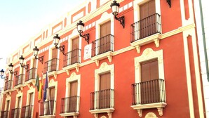 A red building with multiple balconies and ornate architectural details. - Bellido (Montilla)
