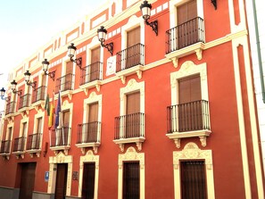A red building with multiple balconies and ornate architectural details. - Bellido (Montilla)