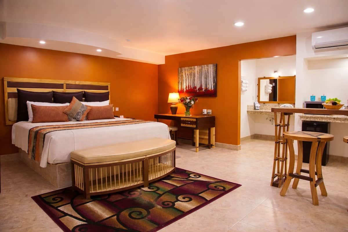 Ein Hotelzimmer mit Bett, Schreibtisch, Stuhl und einer kleinen Küchenzeile.