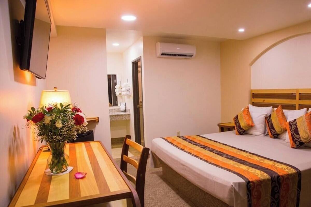 Ein Hotelzimmer mit Bett, Nachttisch, Lampe und einem Blumenstrauß.