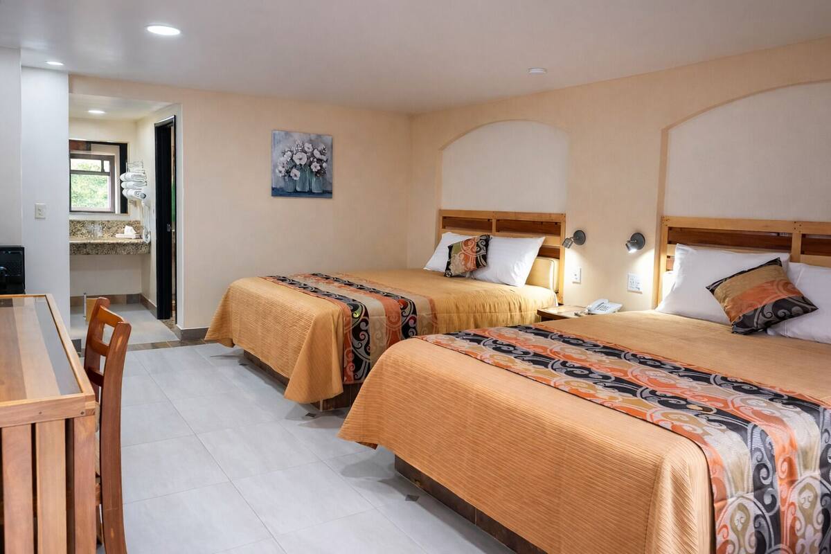 Ein Hotelzimmer mit zwei Betten, einem Esstisch und einer Küchenzeile.