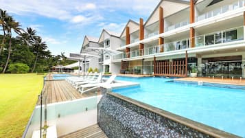 Um hotel com piscina, espreguiçadeiras e área de deck.