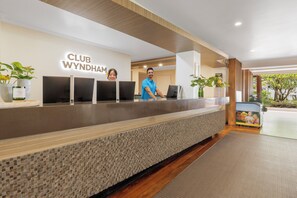 Un comptoir d’accueil avec une enseigne « CLUB WYNDHAM », deux écrans et une personne derrière.