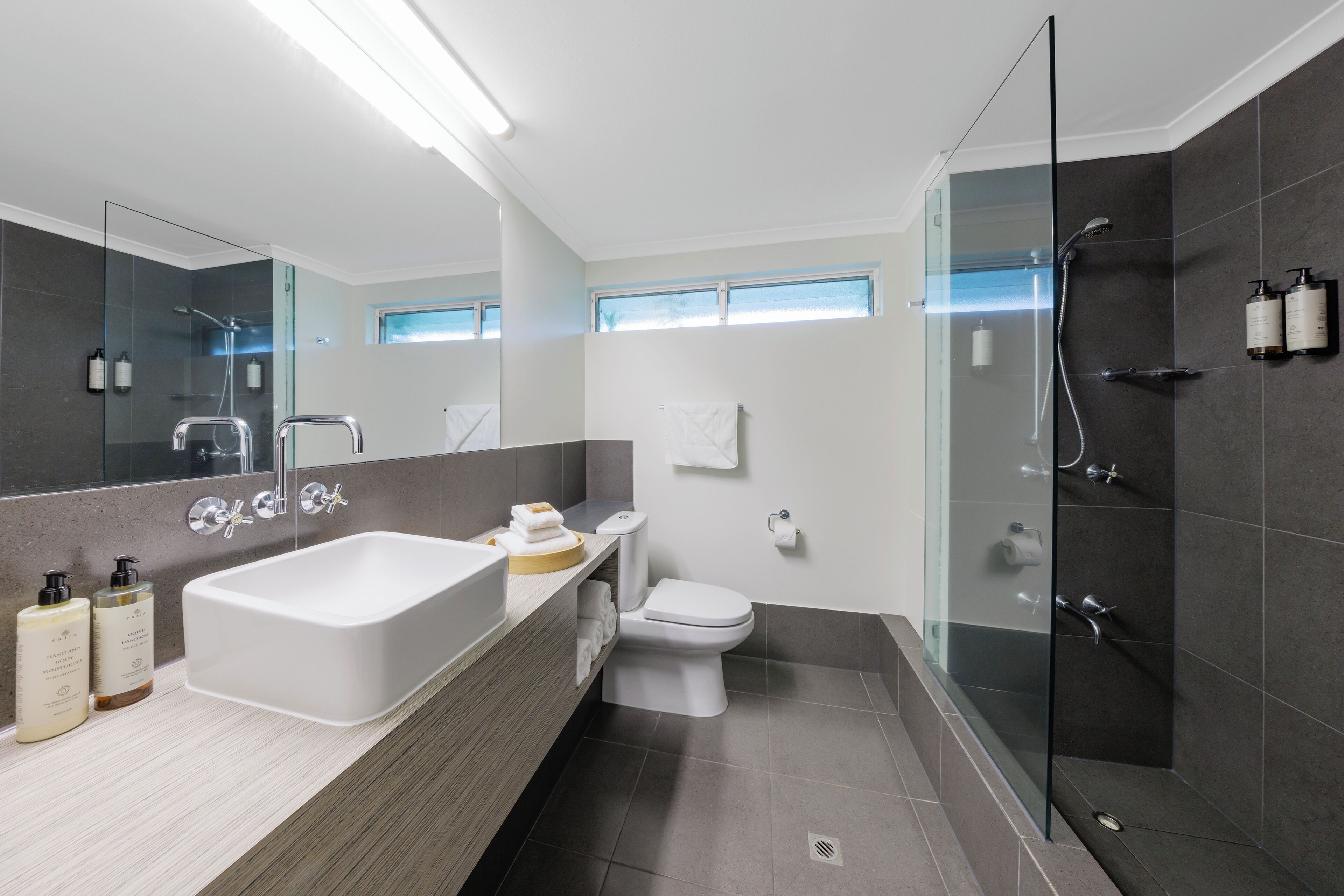 Ein modernes Badezimmer mit einer Glaskabine zur Dusche, einer großen Badewanne und einem WC.