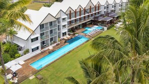 A resort with a long swimming pool, multiple balconies, and lush greenery. - Club Wyndham Mission Beach (Mission Beach)