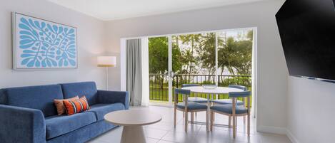 A modern living room with a blue sofa, a round coffee table, and a dining set.