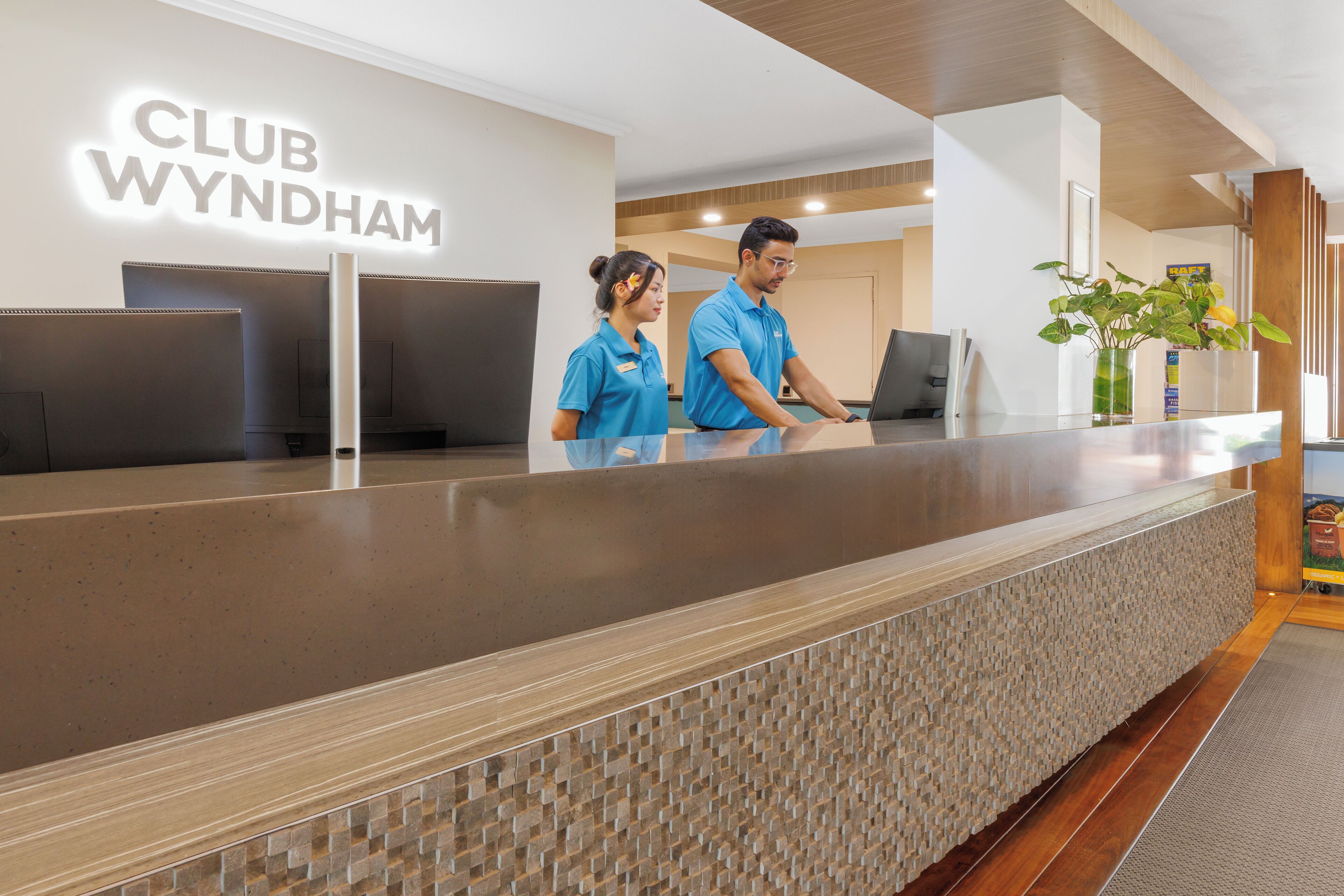 A reception desk at Club Wyndham with a modern design, including a textured wall and a wooden floor.