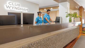 Un mostrador de recepción en Club Wyndham con un diseño moderno, que incluye una pared texturizada y un suelo de madera.