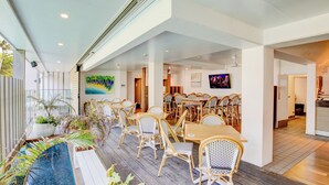 A spacious indoor dining area with multiple tables and chairs, a long counter, and a view of the outdoors. - Club Wyndham Mission Beach (Mission Beach)