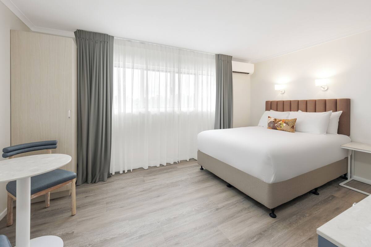 A hotel room with a bed, a desk, and a chair.
