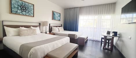 A hotel room with two beds, a desk, a chair, a ceiling fan, and artwork on the walls.