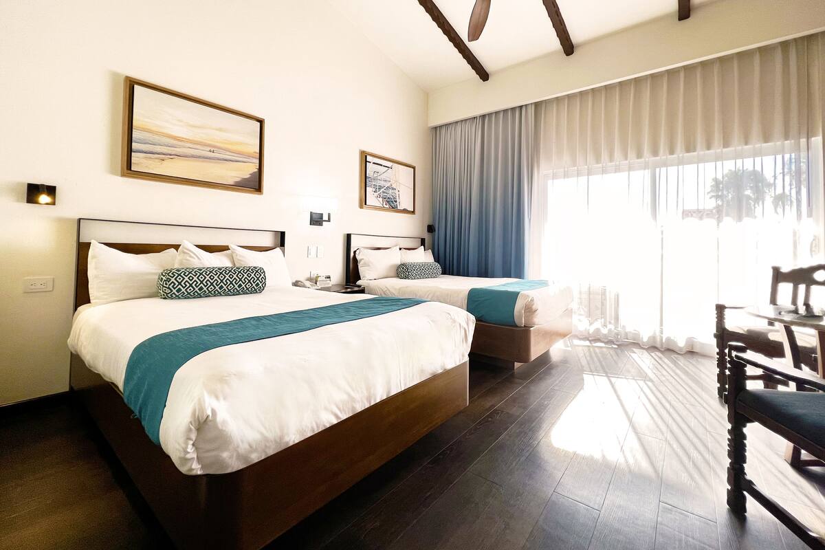 Een hotelkamer met twee bedden, een eettafel en een plafondventilator.
