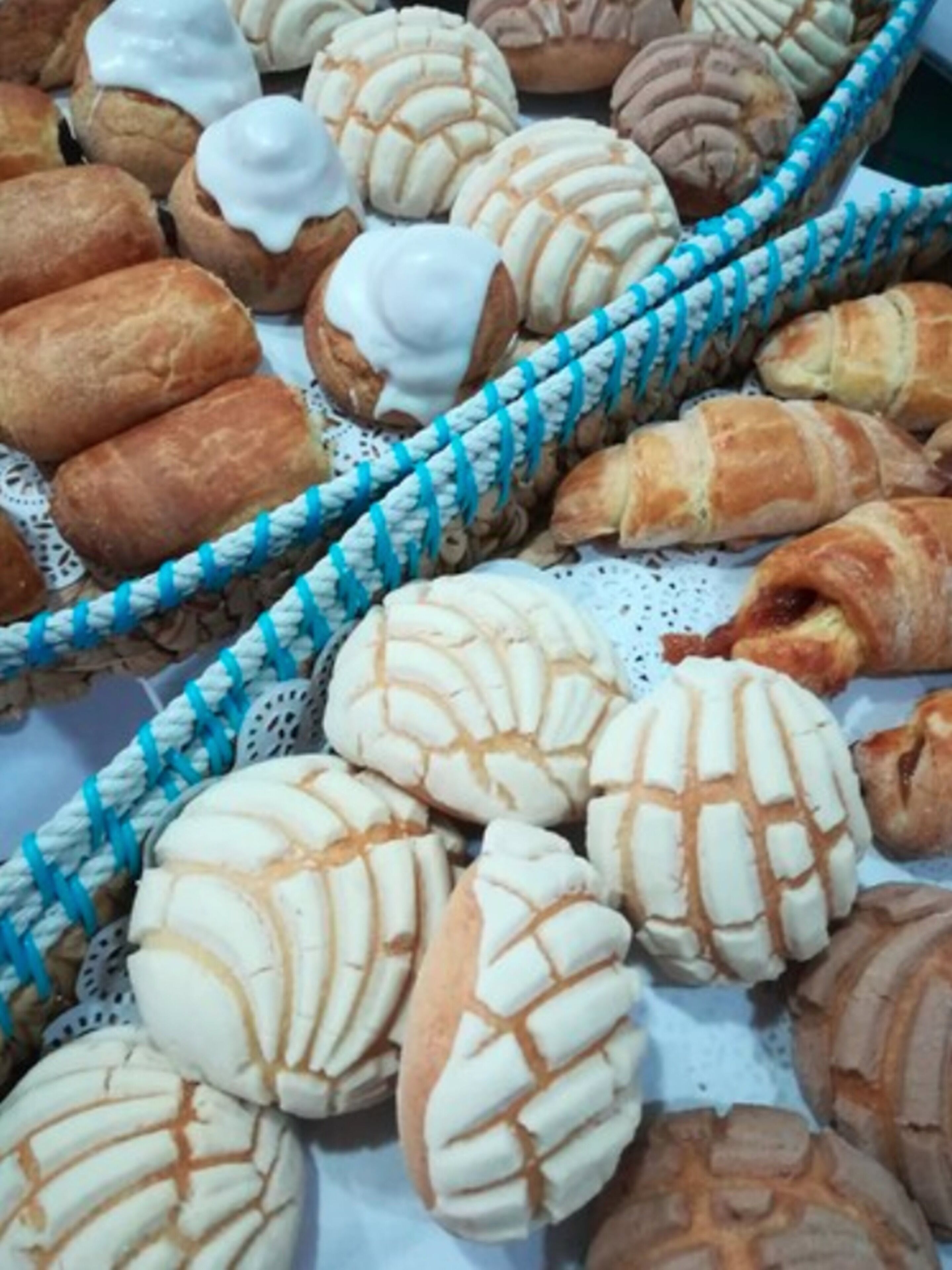 A variety of baked goods, including bread rolls and pastries, displayed in a basket.