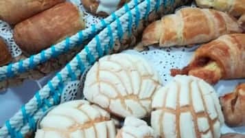 A variety of baked goods, including bread rolls and pastries, displayed in a basket.