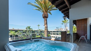 Un jacuzzi en un balcón con vistas a palmeras y edificios.