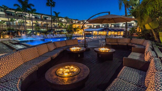 Un área junto a la piscina con sillones y sofás, un jacuzzi y una piscina.