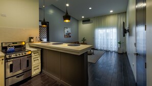 Una cocina moderna con una isla central, horno empotrado e iluminación colgante.