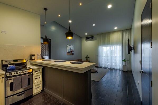 Una cocina moderna con una isla central, horno empotrado e iluminación colgante.