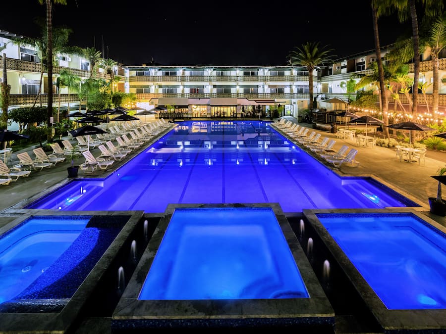 A pool area with multiple swimming pools, lounge chairs, and umbrellas.