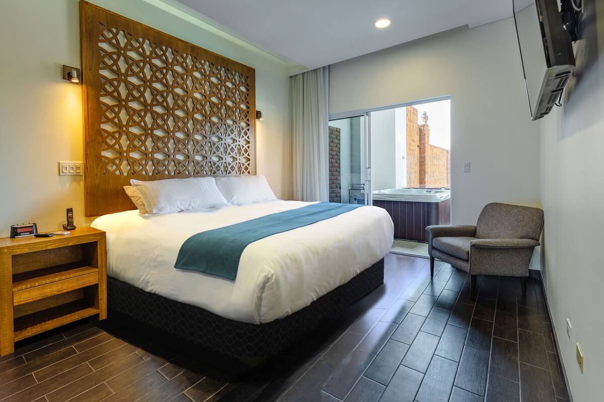 Een hotelkamer met een groot bed, een houten nachtkastje, een stoel en uitzicht.