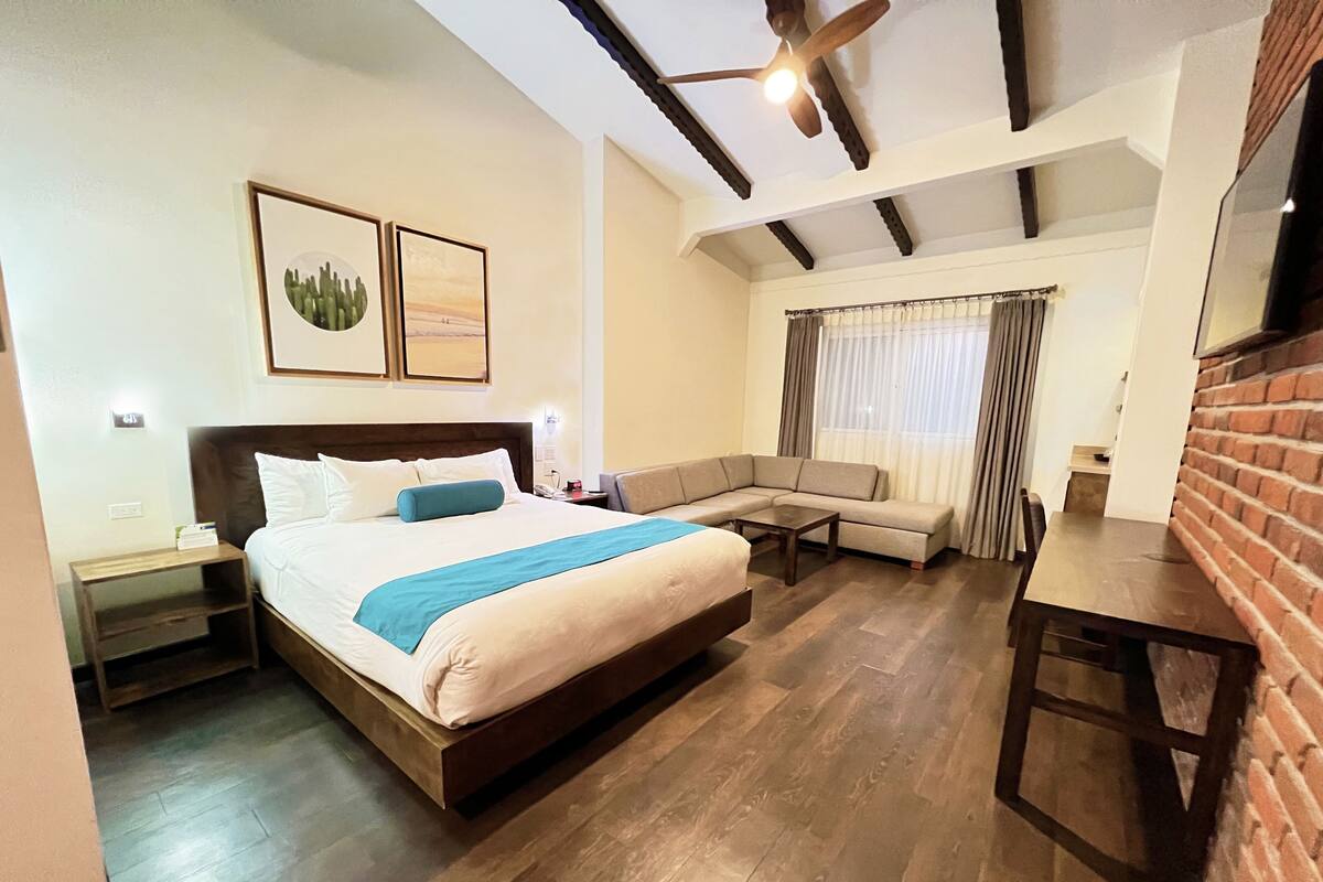 Een hotelkamer met een groot bed, een bank, een klein tafeltje en een televisie.