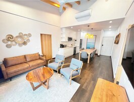 Una sala de estar moderna con un sofá, dos sillones, una mesa de centro y un comedor con mesa y sillas.