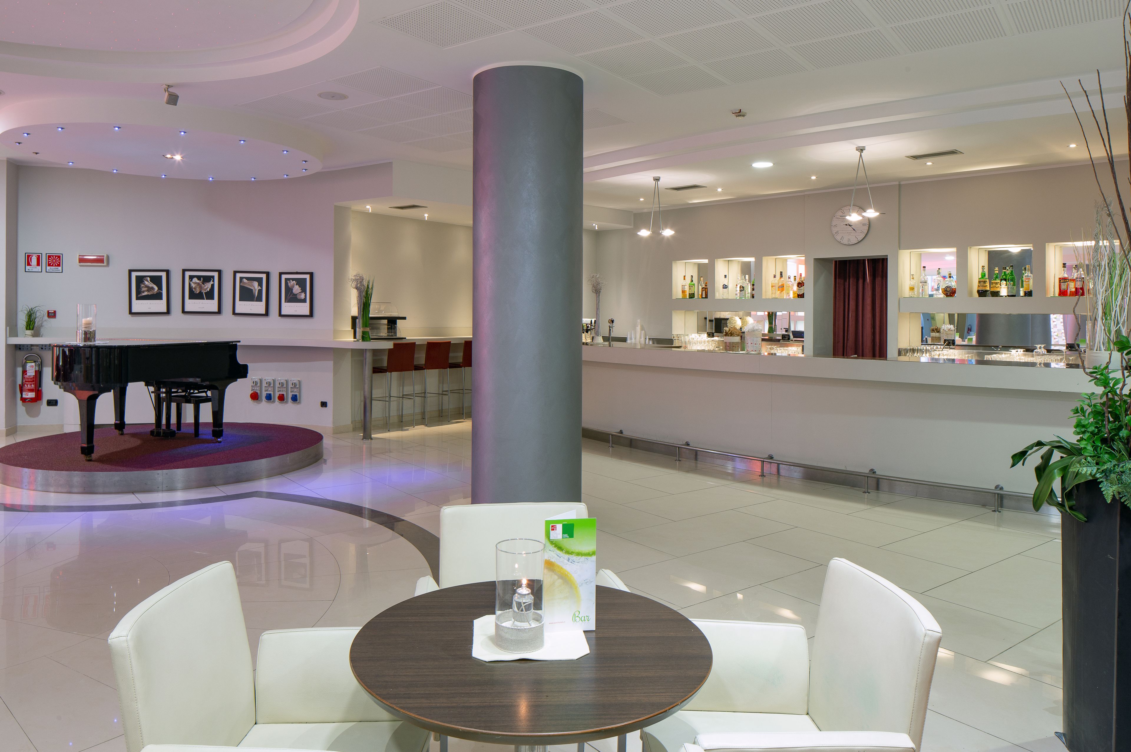 Eine moderne Lobby mit Klavier, Barbereich und einer Sitzecke mit Tisch und Stühlen.