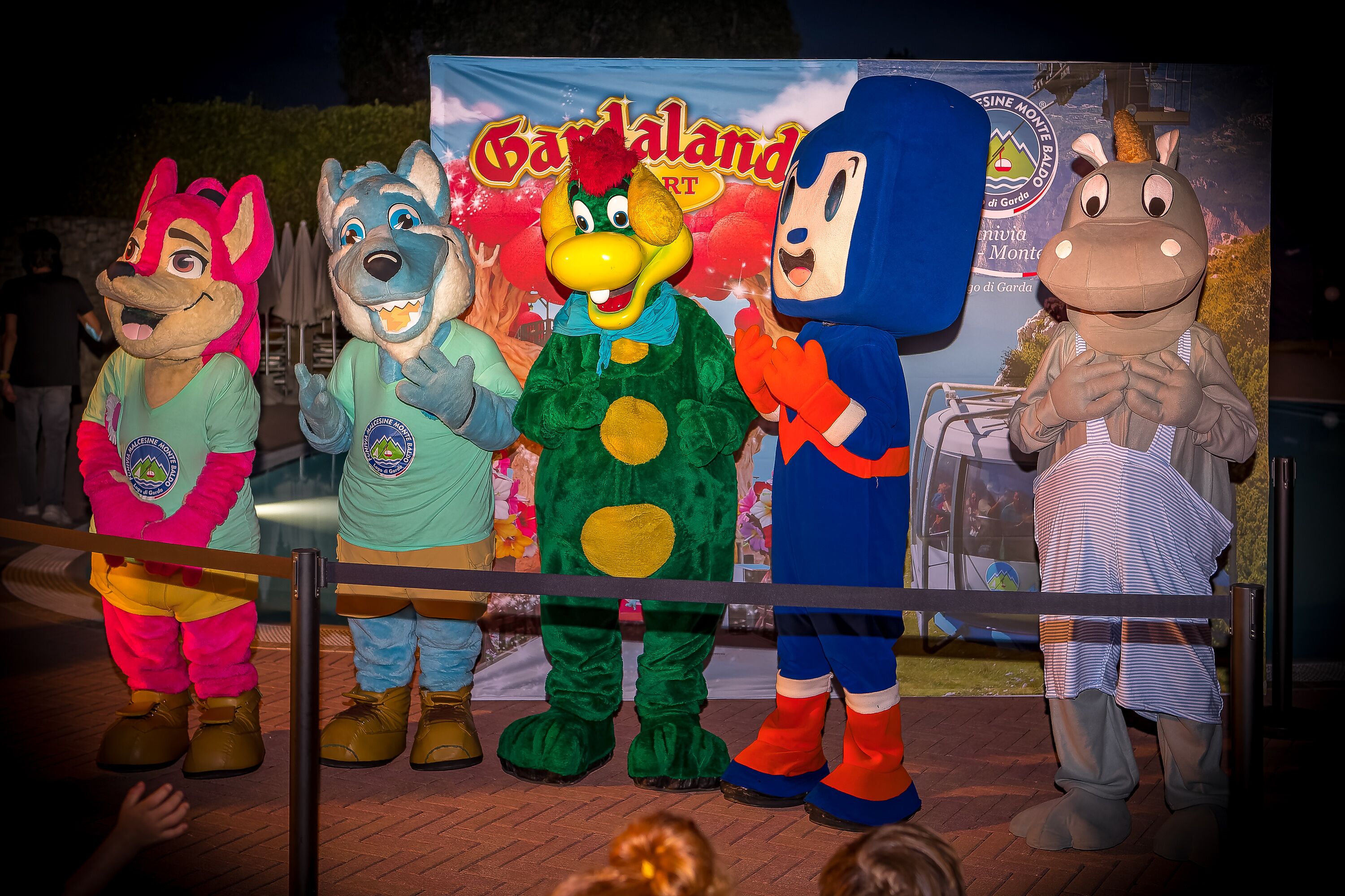 A group of mascots standing on a stage with a banner in the background.