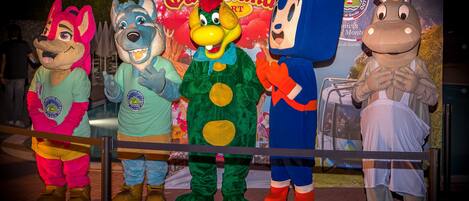 A group of mascots standing on a stage with a banner in the background.